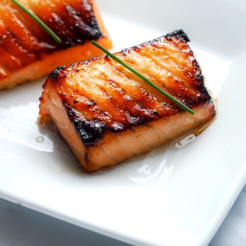 two pieces of salmon on a white plate