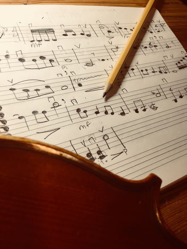 sheet music with pencil on top of it sitting on a table next to a wooden chair