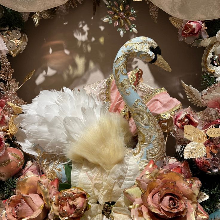 a white swan surrounded by pink roses and other decorations