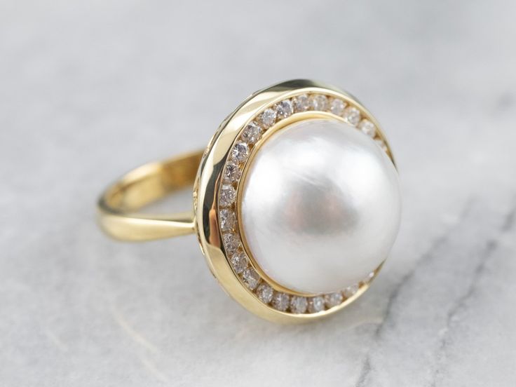 This oversized cocktail ring is filled with shades of soft pink and white! This is a half mabe pearl, shining bright and filled with luster. Surrounding the pearl is a halo of high-quality diamonds, bringing glitter and light into this dreamy statement piece. Metal: 18K Yellow Gold Gem: Mabe Pearl Gem Measurements: 14.4 mm, Round Accents: 28 Diamonds totaling .84 Carats, SI2 in Clarity, H in Color Ring Size: 7.5 Marks: “18K” Stamped on the inside band Pearl Halo Ring, Pearl Ring Design, Pearl Cocktail Ring, Pearl Art, Pearl Cufflinks, Freshwater Pearl Drop Earrings, Ring Pearl, Gold Pearl Ring, Mabe Pearl