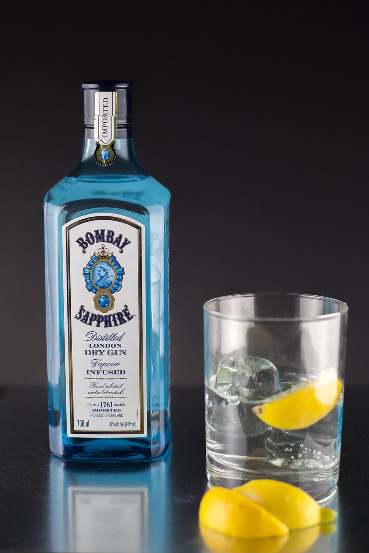 a bottle of vodka next to a glass filled with ice and lemon wedges