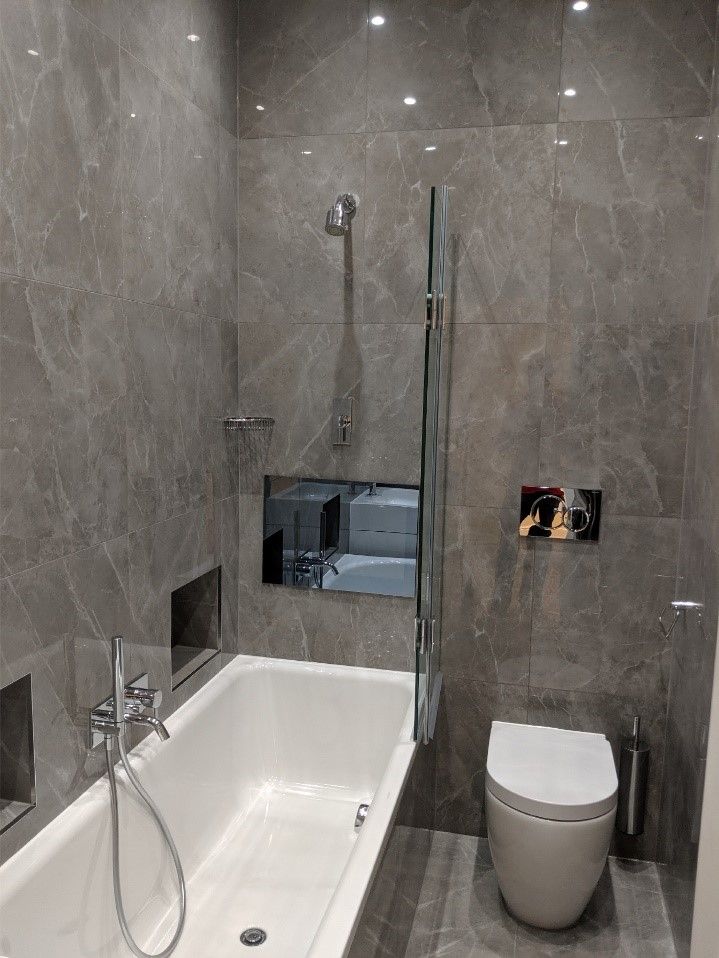 a bathroom with a tub, toilet and shower head mounted to the side of the wall