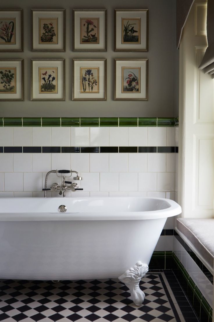 an old fashioned bathtub in a bathroom with pictures on the wall