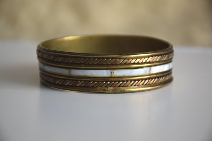 Vintage chunky bangle bracelet, with inlaid pieces of mother of pearl in the middle and rope-like decoration on both sides of it, featuring mixed metals (copper and brass). Handmade in India Era - 80s / 90s.  Diameter (on inside) - 2.55 inches / 6.5 cm Height - 0.7 inches / 1.8 cm Condition: Good to Very good vintage condition with visible imperfections of the execution, see photos Bracelets Hippie, Festival Bracelets, Hippie Bracelet, Hippie Bracelets, Brass Bracelet, Bracelet Boho, Gold Bangle, Copper And Brass, Boho Festival