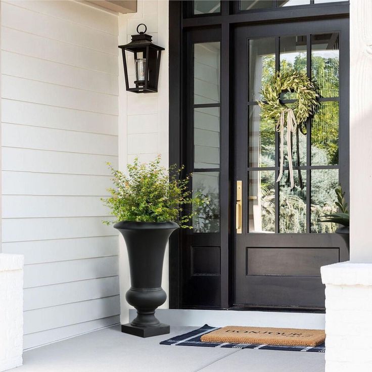 a black front door with potted plants on the porch