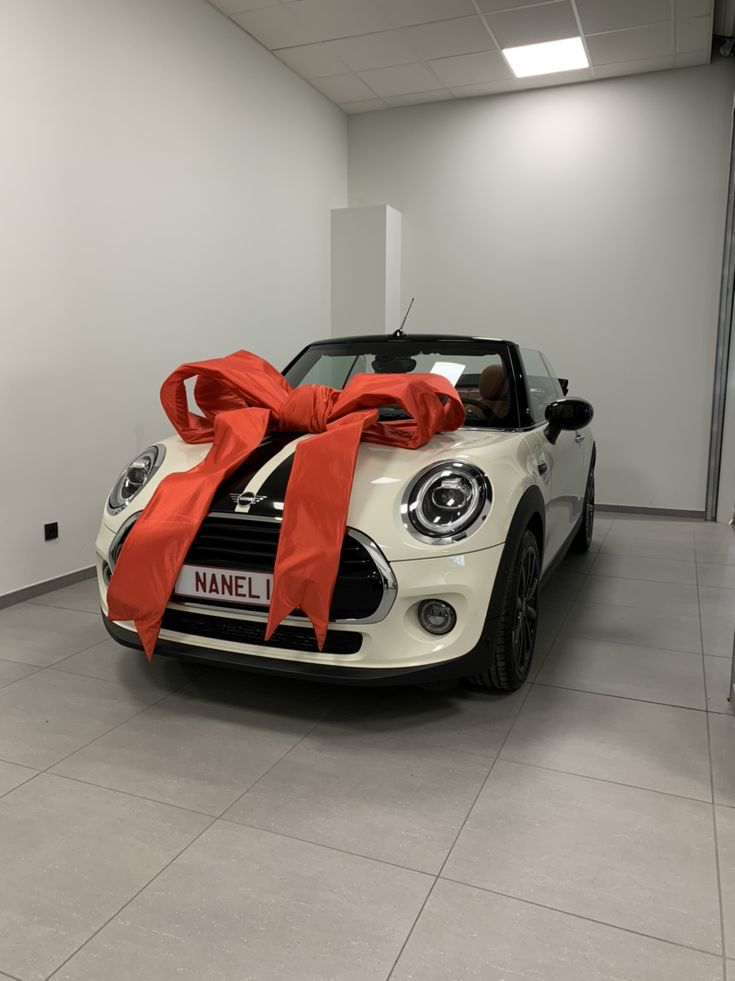 a white car with a red bow on it's hood in a showroom