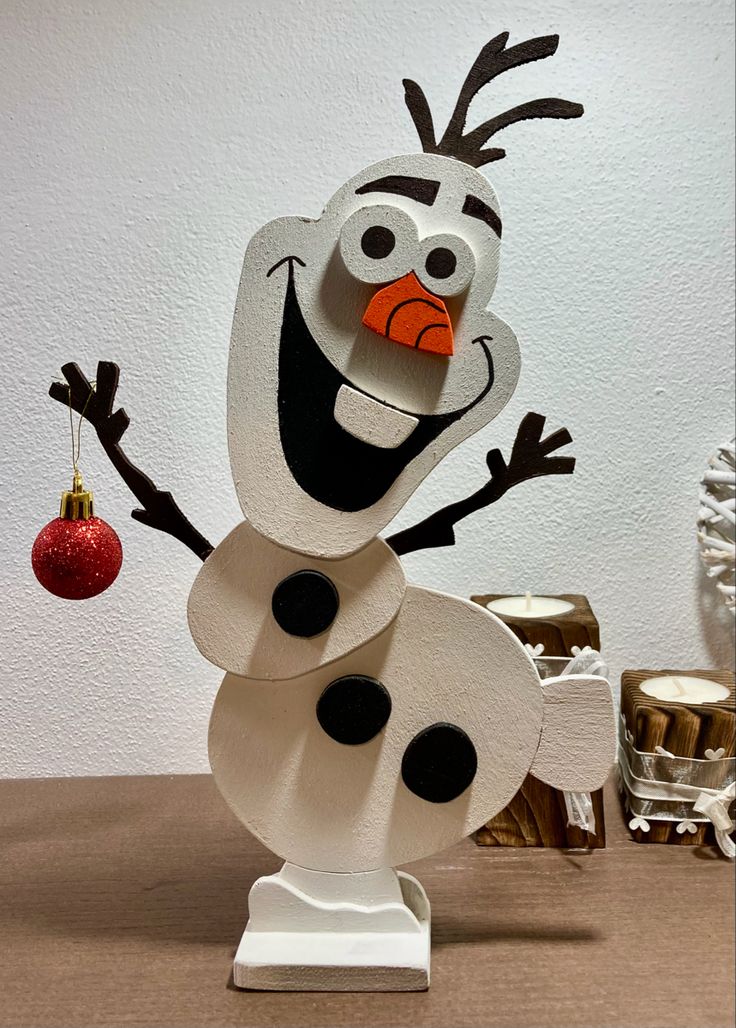 a paper snowman ornament with a red ball hanging from it's nose