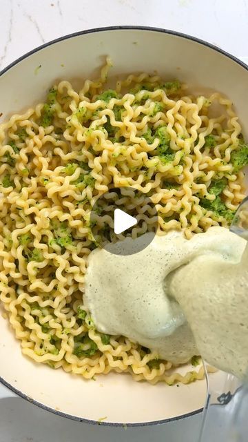 a bowl filled with noodles and broccoli being poured into the pot to make it