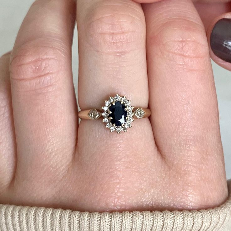 a woman's hand with a ring on it and a blue stone in the middle