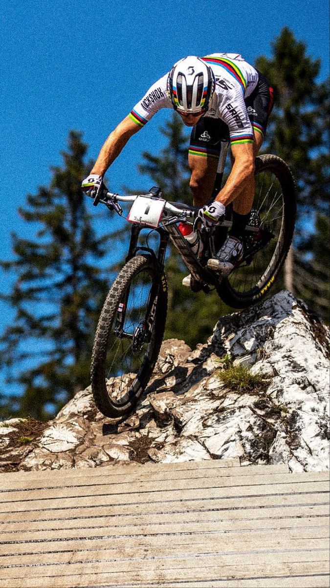 a man riding a bike up the side of a wooden ramp on top of a mountain