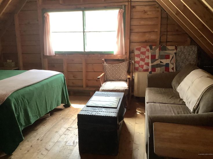 a bedroom with a bed, couch and chair in it's attic area next to a window