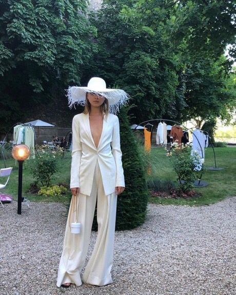 a woman wearing a white suit and hat