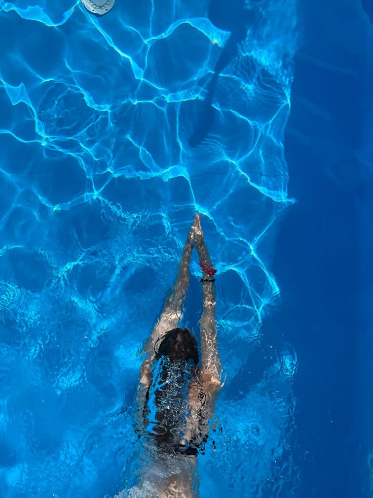 a person swimming in a pool with a frisbee