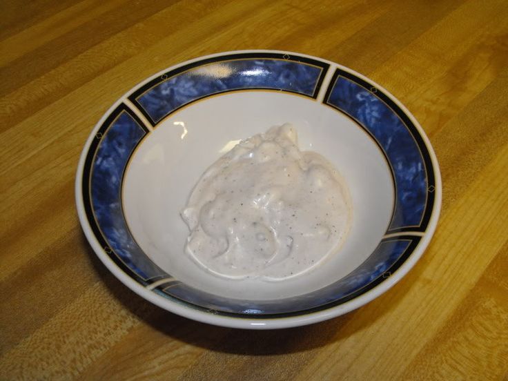 a white and blue bowl filled with food on top of a wooden table