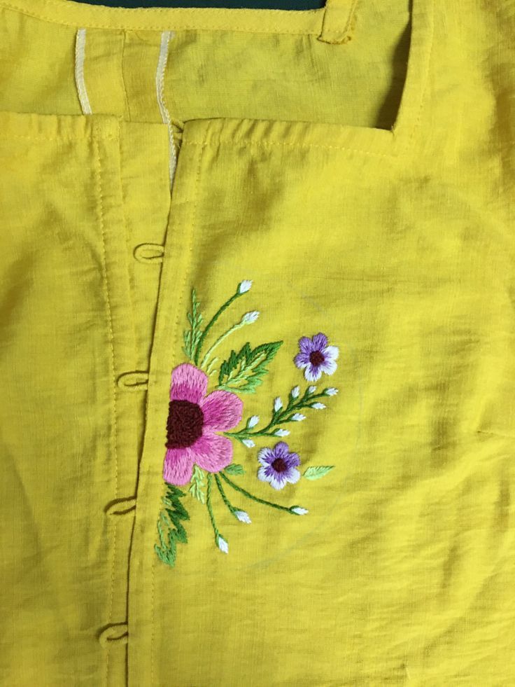 a yellow shirt with flowers embroidered on it