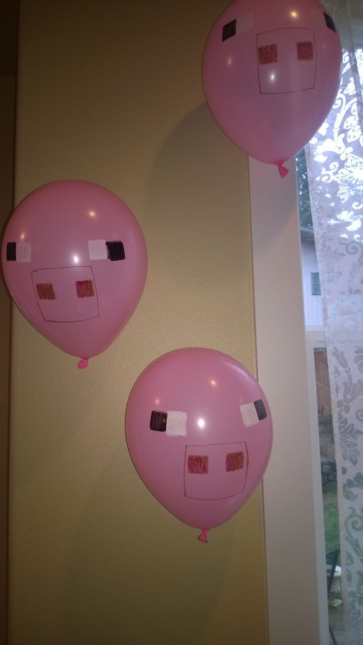 two pink balloons hanging from the side of a wall