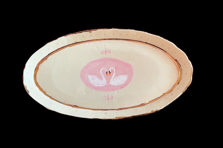 a pink and white plate with a bird on it's side, against a black background