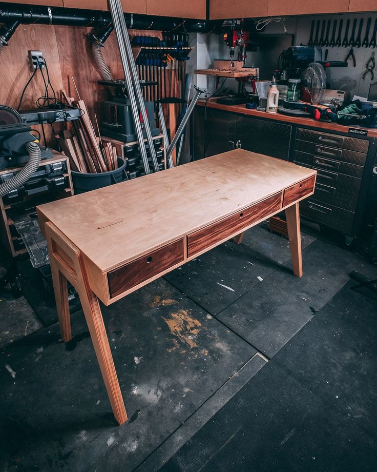 a wooden table in a garage with tools on the counter and other workbench behind it