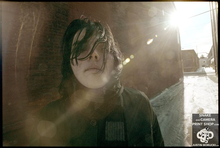 a woman standing in front of a brick wall with the sun shining through her hair