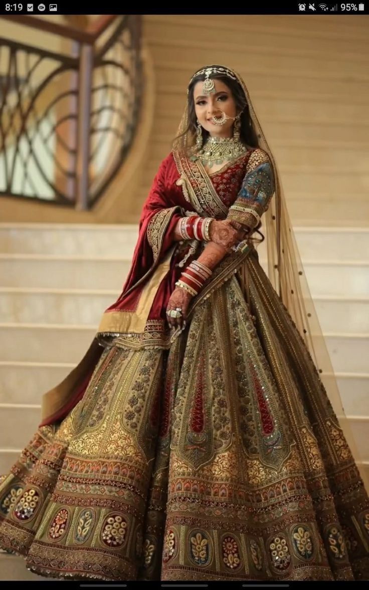 a woman in a red and gold bridal gown posing for the camera with her hands on her hips