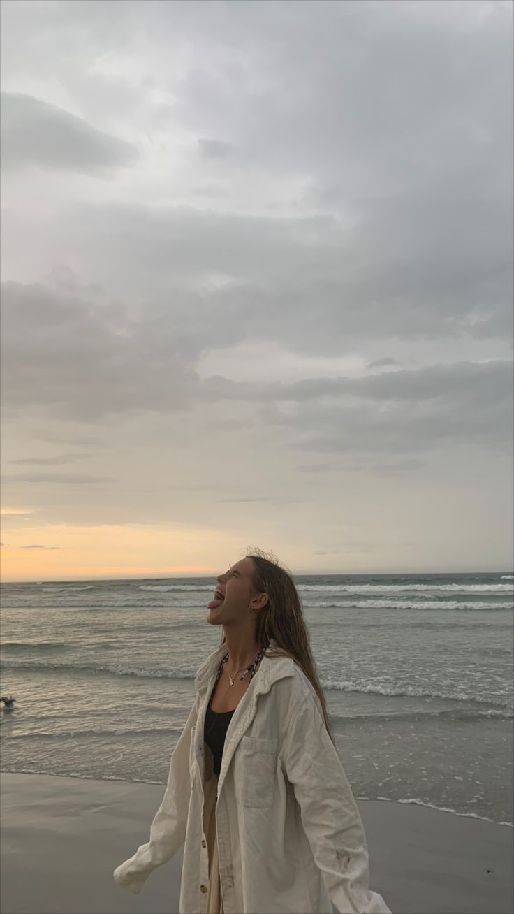 a woman standing on top of a beach next to the ocean