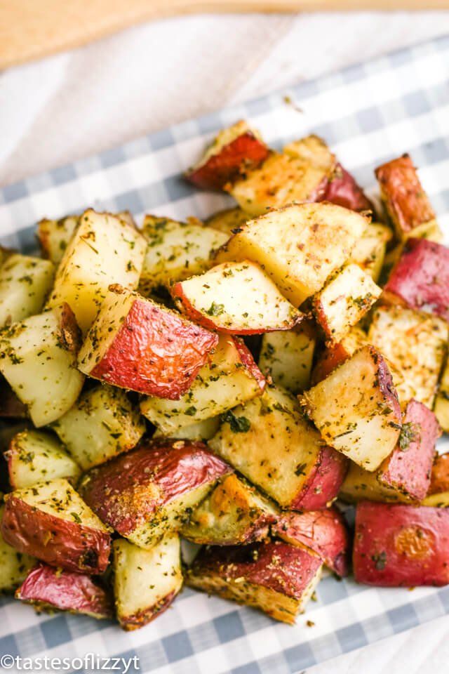 cooked potatoes with herbs and seasoning sitting on a checkered paper towel, ready to be eaten