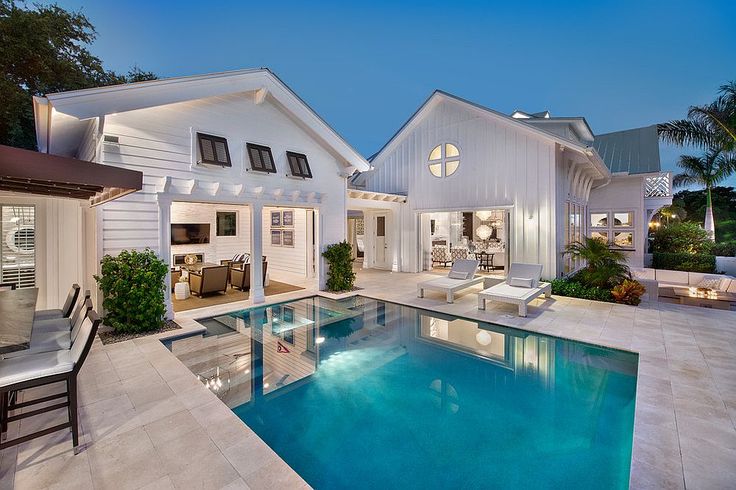 a house with a swimming pool in front of it and an outdoor lounge area next to the pool