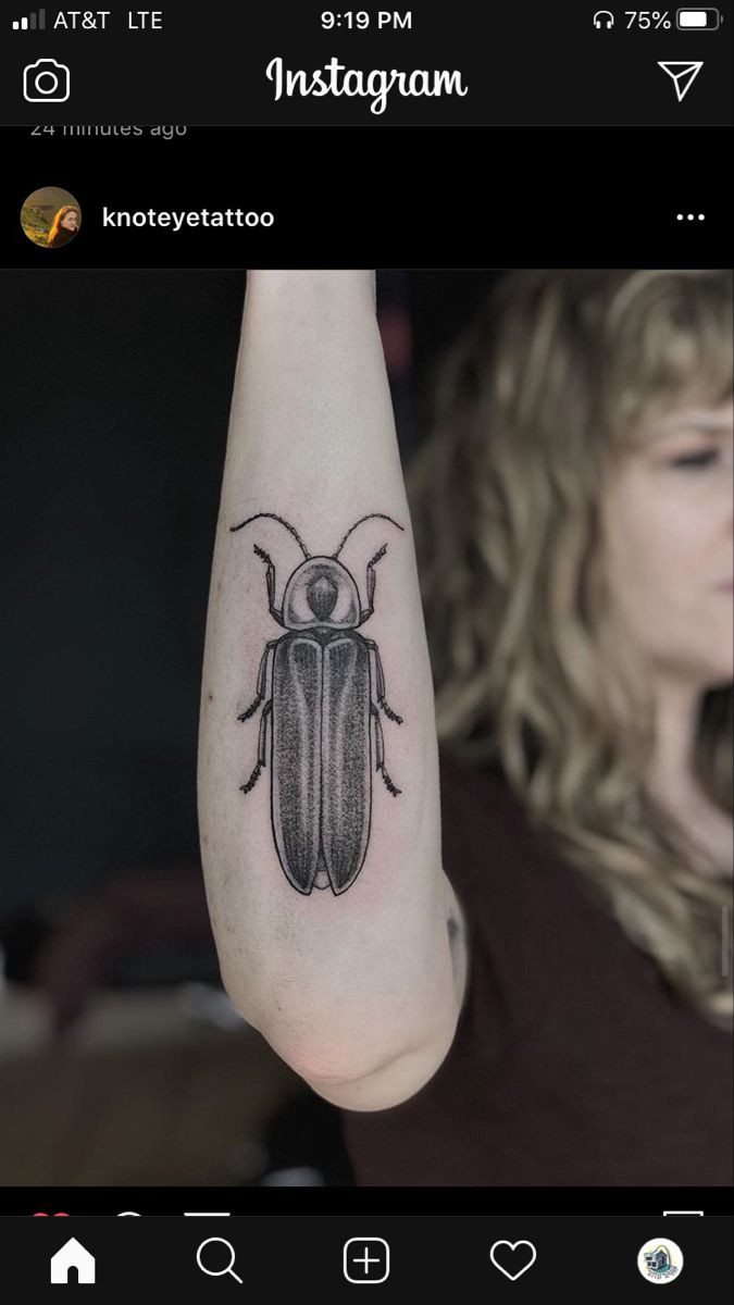 a woman with a tattoo on her arm holding up a small bug in the air