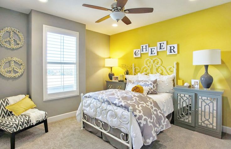 a bedroom with yellow walls and gray furniture