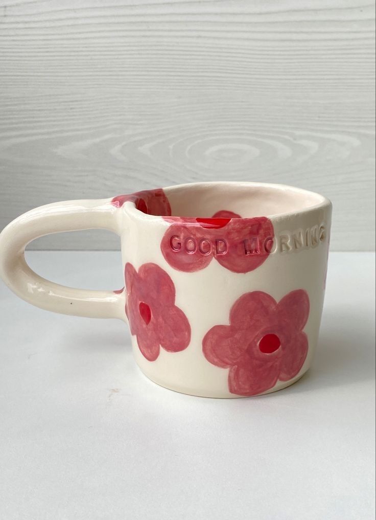 a pink and white coffee cup with red flowers on the inside is sitting on a table