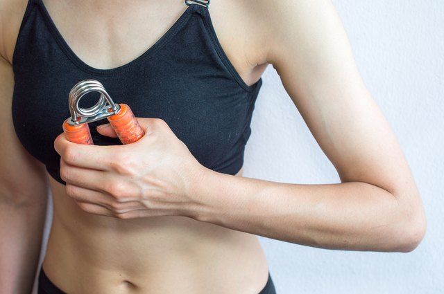 a woman holding an orange object in her right hand and wearing a black bra top