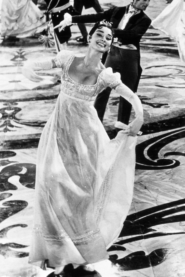 a man and woman in formal dress dancing on the dance floor with other people behind them