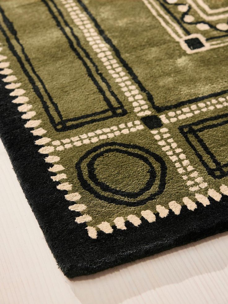 a green and black area rug on top of a white table with a wooden floor