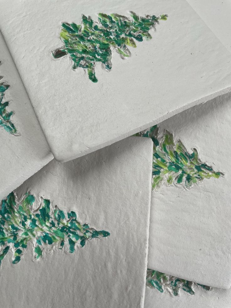 four pieces of white paper with green leaves on them