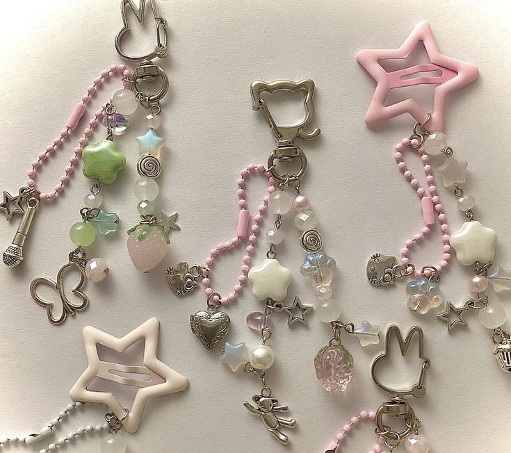 several charms are arranged together on a white surface with pink and green beads, pearls, and other items