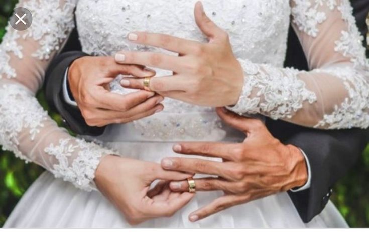 the bride and groom are holding each other's hands while they hold their wedding rings