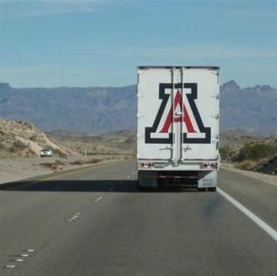 a semi truck driving down the highway with mountains in the background