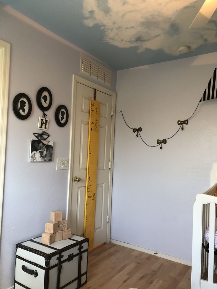 a baby's room is decorated in blue and white with clouds painted on the ceiling