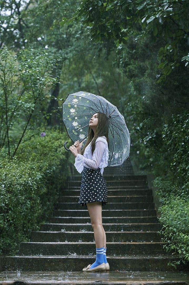 a woman holding an umbrella standing on steps in the rain