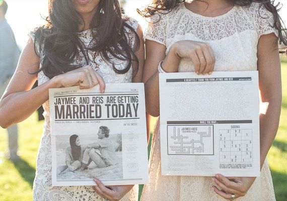 two women are holding up newspapers with pictures on them and one is reading married today