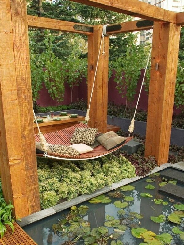 a hammock hanging in the middle of a garden with water lilies and plants