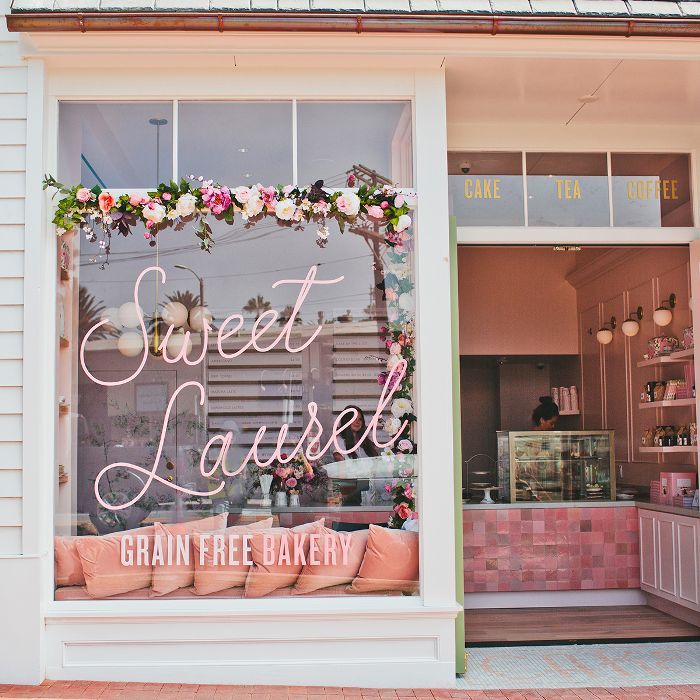 the front window of sweet lauren's bakery with pink flowers and greenery on display