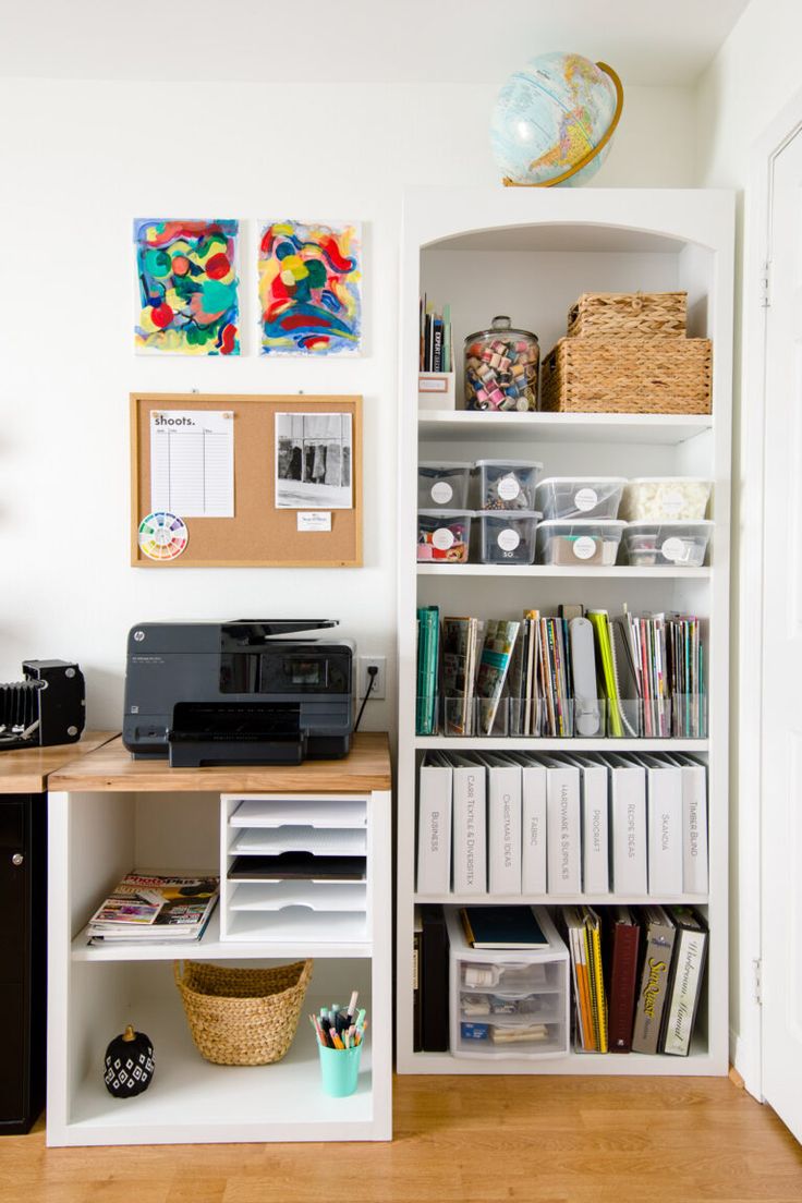 a white bookcase filled with lots of books next to a printer and other office supplies