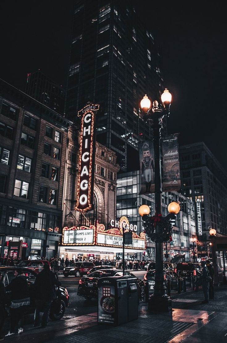 a city street at night with tall buildings