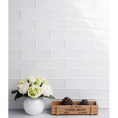 white roses in a vase next to a wooden box with pine cones on the side