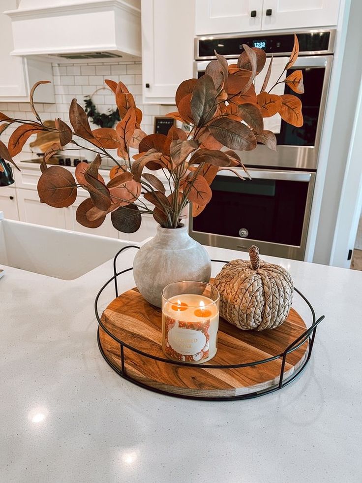 a kitchen counter with a candle, potted plant and pumpkins on the tray