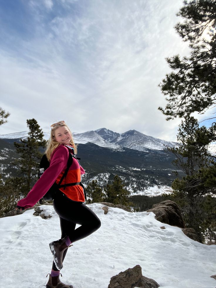 a woman standing on top of a snow covered slope