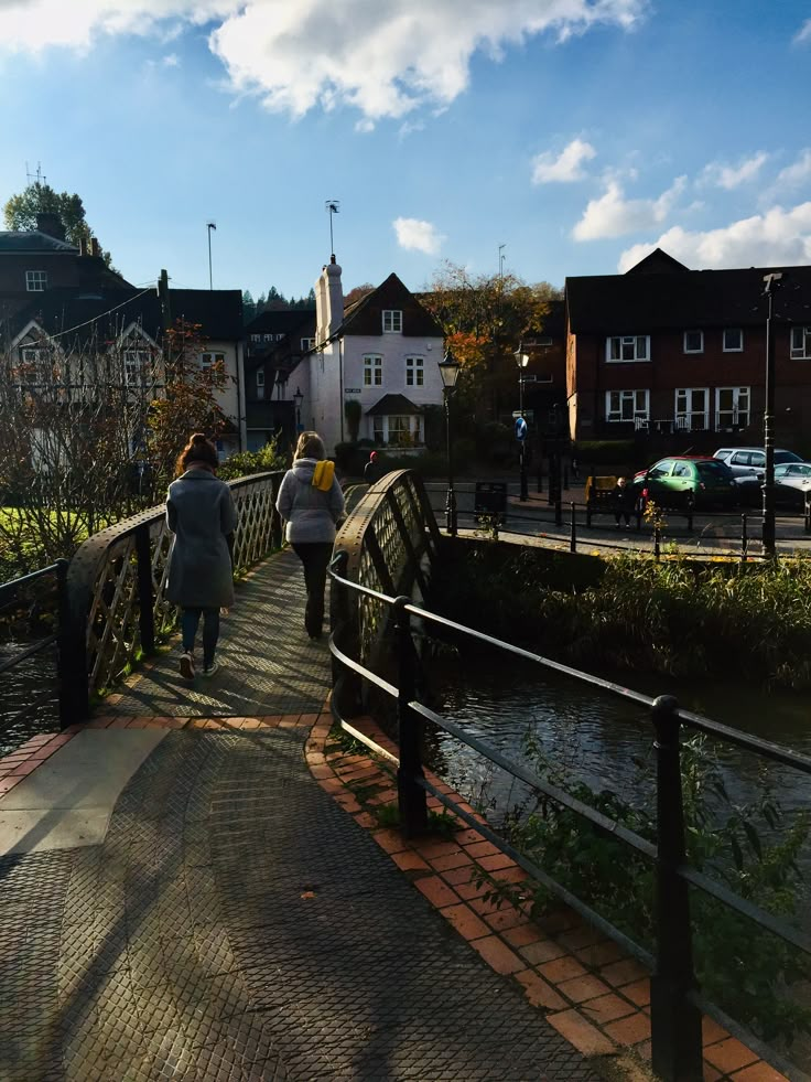 three people walking across a bridge over a river