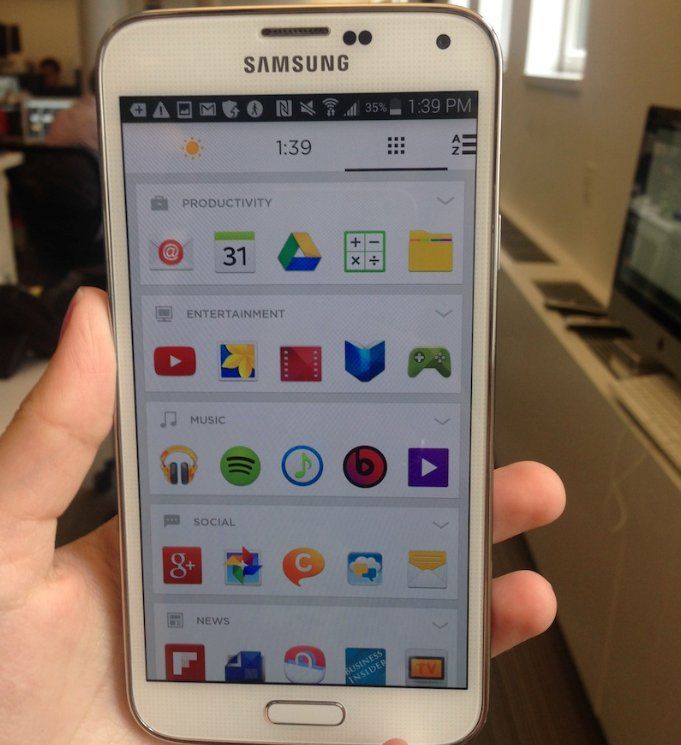 a person holding up a smart phone with icons on the screen in front of them