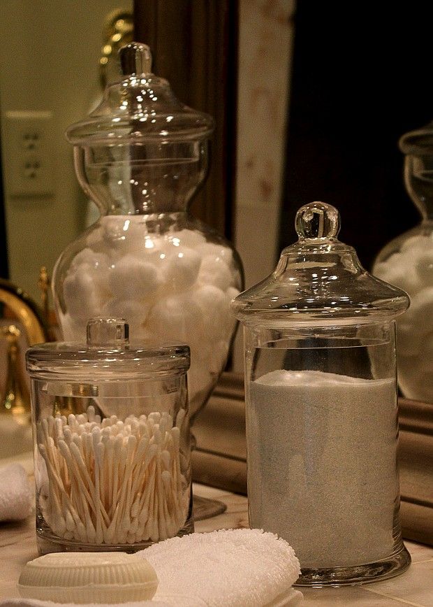 three glass jars filled with different types of bath items on a counter top next to a mirror